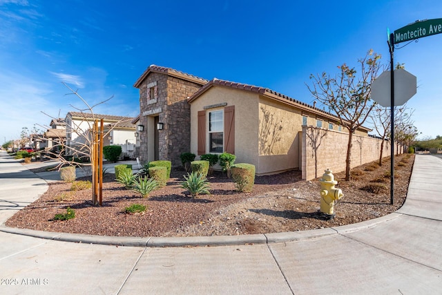 19889 W Montecito Ave, Litchfield Park, AZ 85340 - view of property exterior featuring stucco siding, a tiled roof, and stone siding