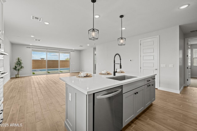 kitchen featuring a sink, dishwasher, light wood-type flooring, open floor plan, and gray cabinetry