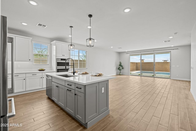 kitchen with gray cabinets, appliances with stainless steel finishes, a sink, light wood-style flooring, and recessed lighting