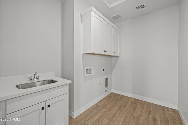 clothes washing area with cabinet space, electric dryer hookup, hookup for a washing machine, light wood-type flooring, and baseboards