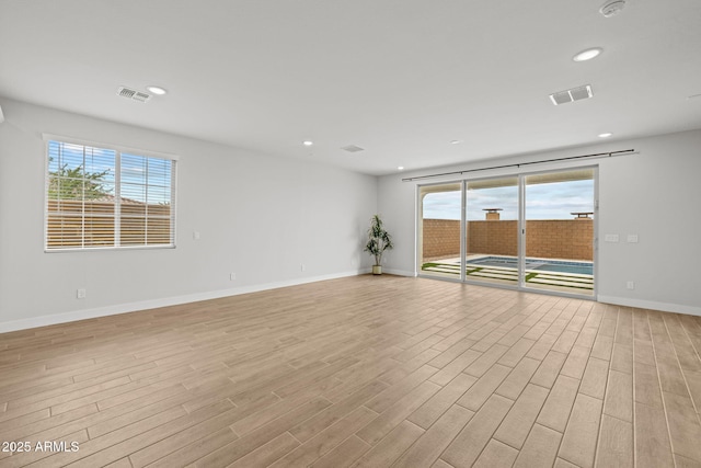 spare room featuring plenty of natural light, light wood-style floors, recessed lighting, and baseboards
