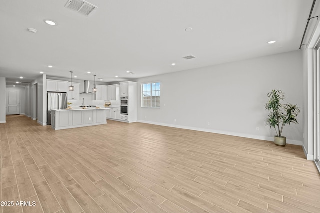 unfurnished living room featuring baseboards, recessed lighting, and light wood finished floors