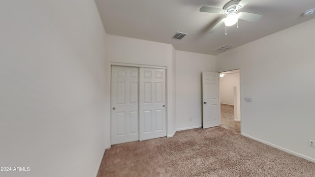 unfurnished bedroom with a closet, light colored carpet, and ceiling fan