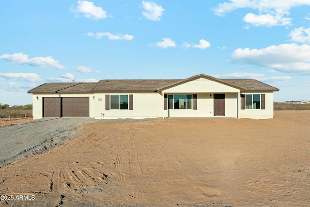 ranch-style house featuring a garage, driveway, and stucco siding