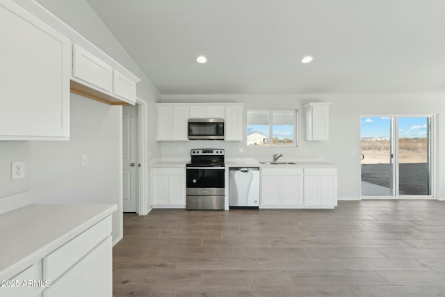 kitchen featuring white cabinetry, stainless steel appliances, a sink, and light countertops