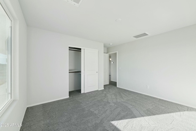 unfurnished bedroom with carpet floors, baseboards, visible vents, and a closet