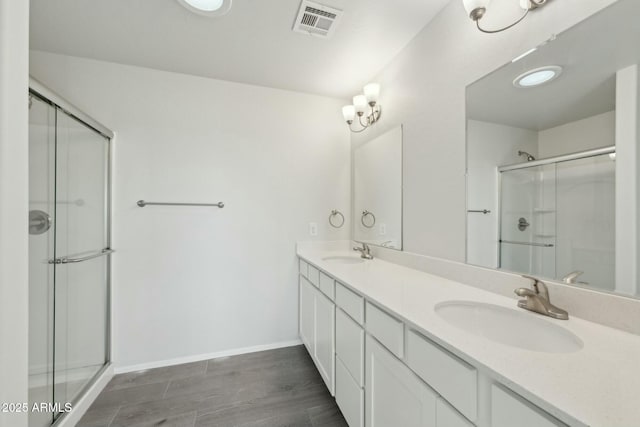 bathroom with visible vents, a sink, a shower stall, and double vanity