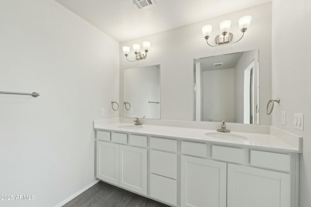 bathroom featuring double vanity, visible vents, a sink, and wood finished floors