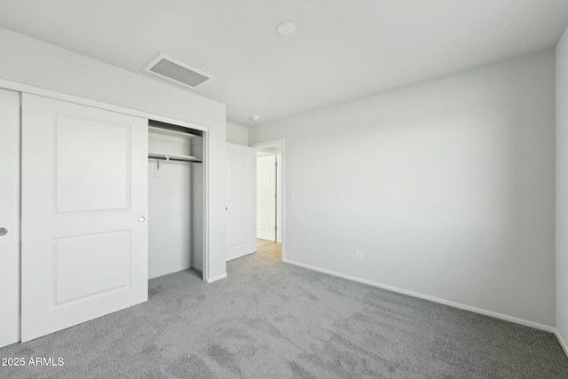 unfurnished bedroom with a closet, visible vents, light carpet, and baseboards