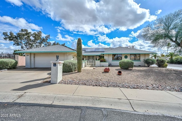 ranch-style house with a garage, solar panels, driveway, and fence