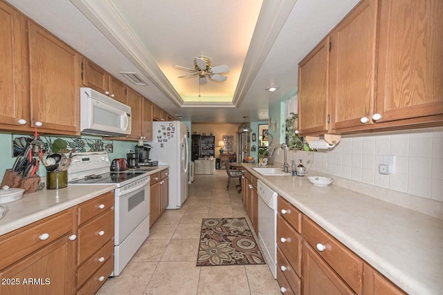 kitchen with ceiling fan, light countertops, white appliances, a raised ceiling, and a sink