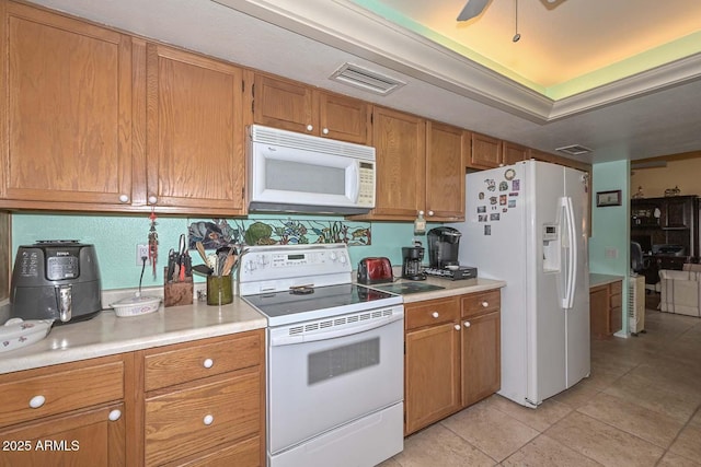 kitchen with visible vents, light countertops, light tile patterned floors, brown cabinetry, and white appliances