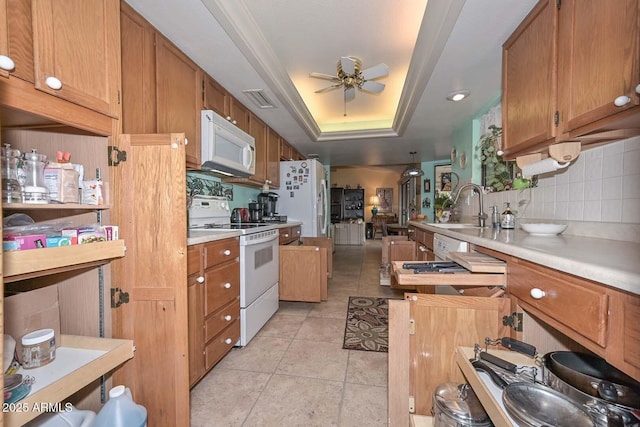 kitchen featuring white appliances, visible vents, a tray ceiling, ceiling fan, and a sink