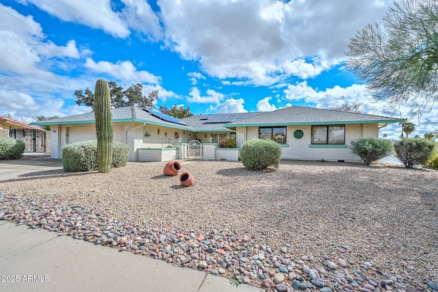 ranch-style home featuring roof mounted solar panels, driveway, an attached garage, and fence