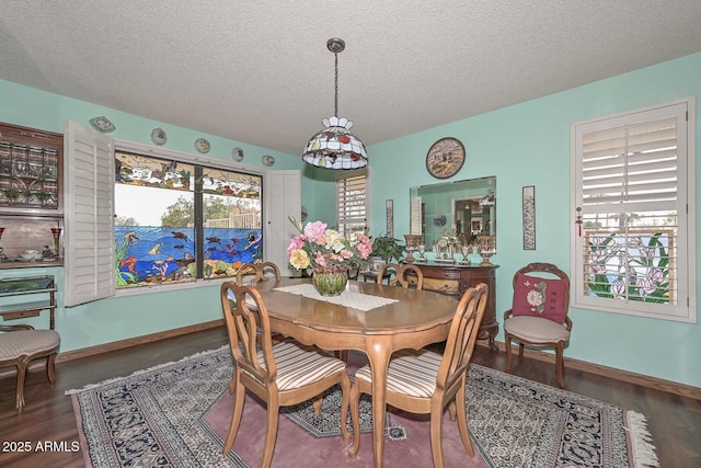 dining room featuring a textured ceiling, baseboards, and wood finished floors