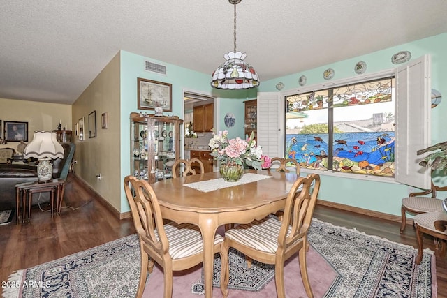 dining space featuring visible vents, a textured ceiling, and wood finished floors