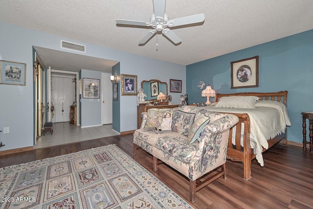 bedroom with visible vents, a textured ceiling, ceiling fan, and wood finished floors