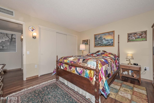 bedroom with visible vents, a textured ceiling, wood finished floors, a closet, and baseboards