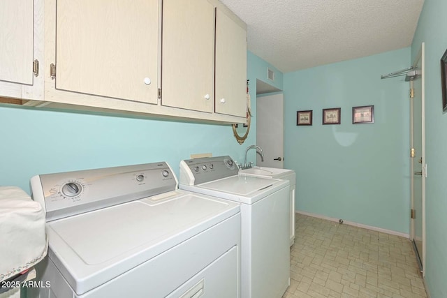 clothes washing area with visible vents, washer and dryer, a textured ceiling, cabinet space, and baseboards