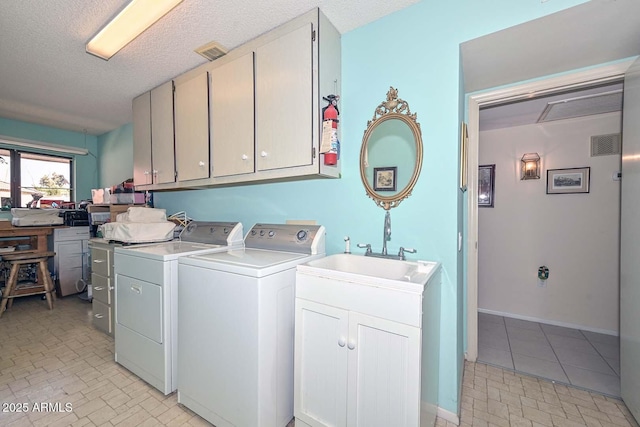 washroom with washing machine and clothes dryer, visible vents, cabinet space, a textured ceiling, and a sink