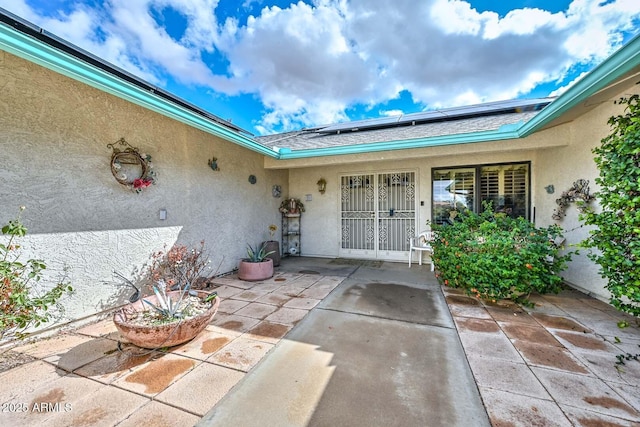 doorway to property featuring a patio area, roof mounted solar panels, and stucco siding