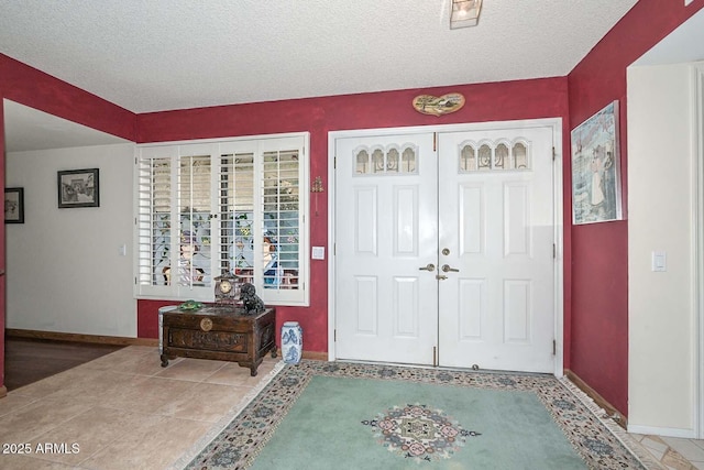 entrance foyer featuring tile patterned floors, a textured ceiling, and baseboards