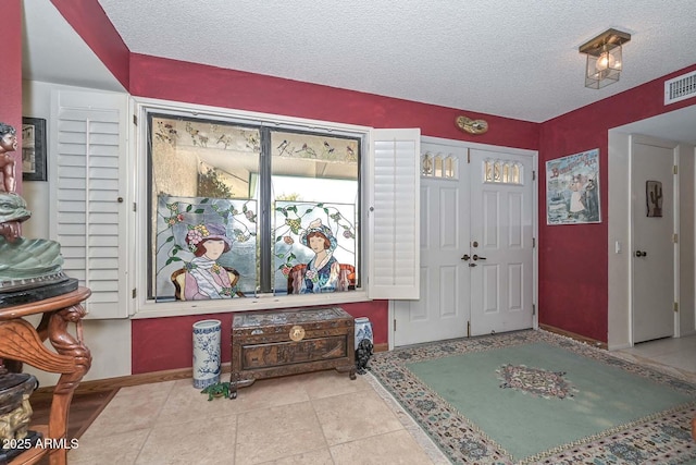 tiled entrance foyer featuring visible vents, baseboards, and a textured ceiling