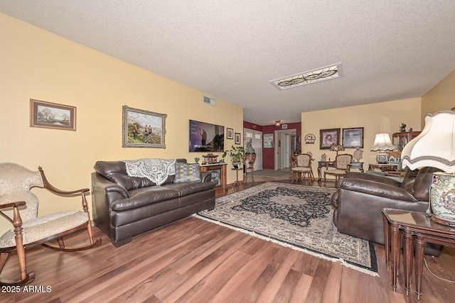 living area featuring wood finished floors, visible vents, and a textured ceiling