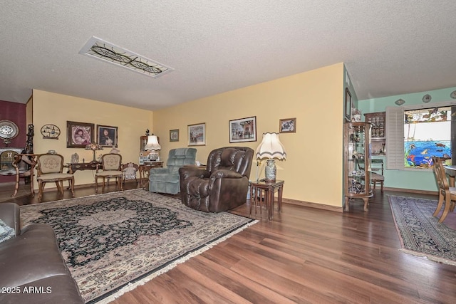 living room with wood finished floors, baseboards, and a textured ceiling