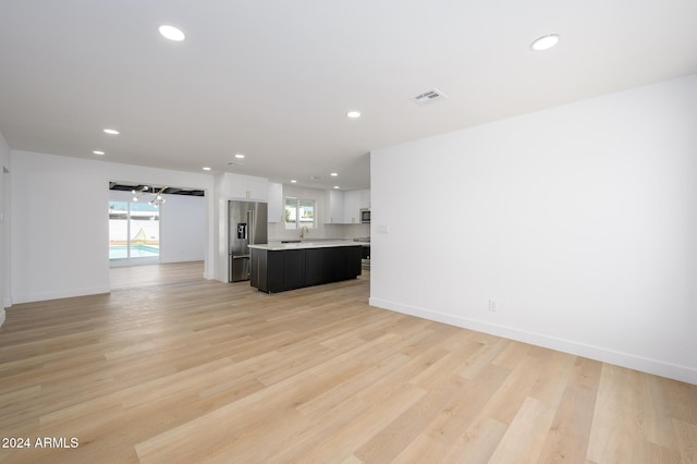 unfurnished living room with light hardwood / wood-style flooring and sink