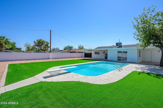 view of swimming pool with a diving board, a yard, a patio, and central AC