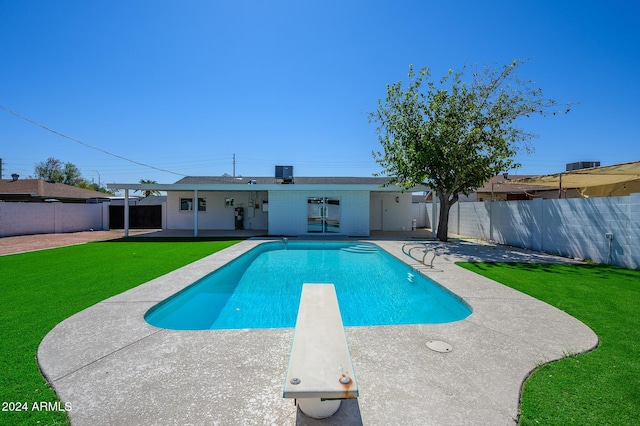 view of swimming pool featuring a yard, a patio, and a diving board