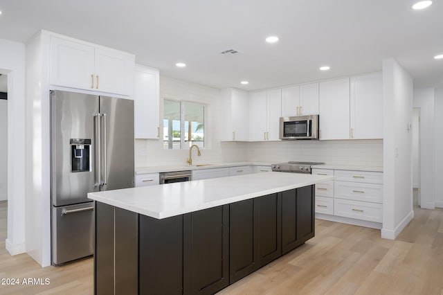 kitchen featuring stainless steel appliances, a kitchen island, white cabinetry, and light hardwood / wood-style flooring