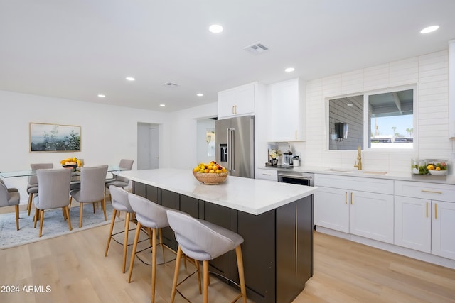 kitchen featuring sink, a kitchen island, light wood-type flooring, high end fridge, and white cabinetry