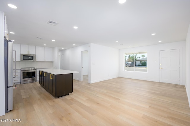 kitchen featuring white cabinets, a kitchen island, light wood-type flooring, and stainless steel appliances