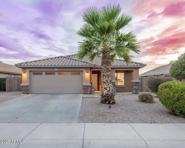 6920 S 46th Dr, Laveen, AZ 85339 - view of front of house featuring stucco siding, an attached garage, concrete driveway, a tile roof, and stone siding