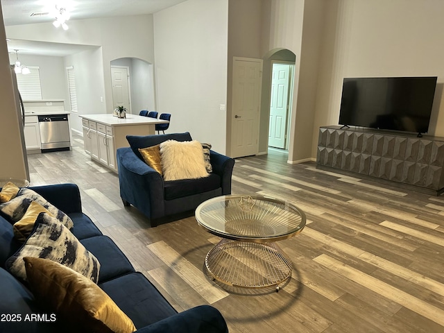 6920 S 46th Dr, Laveen, AZ 85339 - living room featuring arched walkways, light wood finished floors, vaulted ceiling, and baseboards