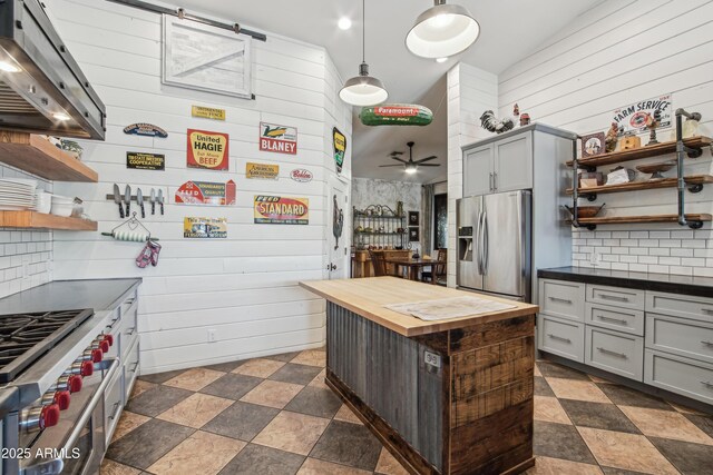 21131 E Excelsior Ave, Queen Creek, AZ 85142 - kitchen featuring stainless steel appliances, open shelves, wooden counters, exhaust hood, and wood walls