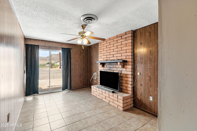 841 W Spray St, Superior, AZ 85173 - unfurnished living room featuring wooden walls, a textured ceiling, ceiling fan, light tile patterned floors, and a brick fireplace