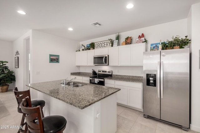 kitchen with white cabinetry, sink, dark stone counters, a kitchen island with sink, and stainless steel appliances