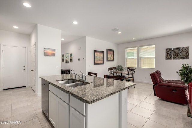 kitchen featuring sink, a kitchen island with sink, white cabinets, stone countertops, and stainless steel dishwasher