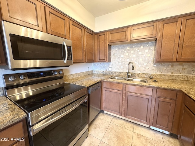 1702 W Tuckey Ln Unit 209, Phoenix, AZ 85015 - kitchen with appliances with stainless steel finishes, a sink, brown cabinets, backsplash, and light stone counters