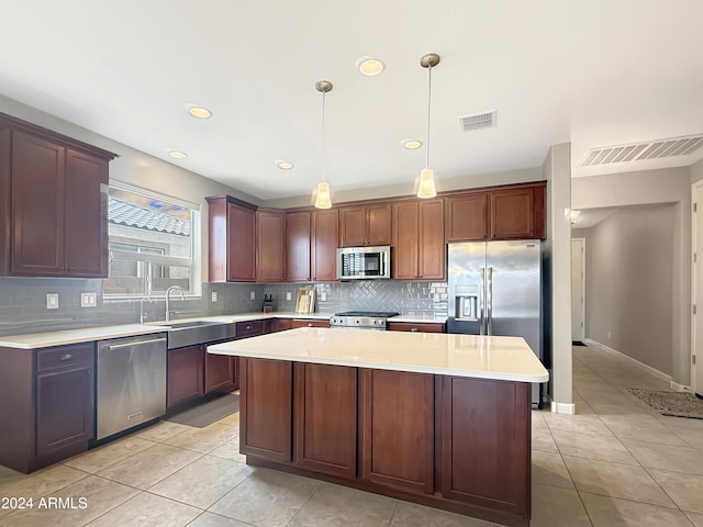 kitchen with appliances with stainless steel finishes, sink, a center island, hanging light fixtures, and light tile patterned flooring