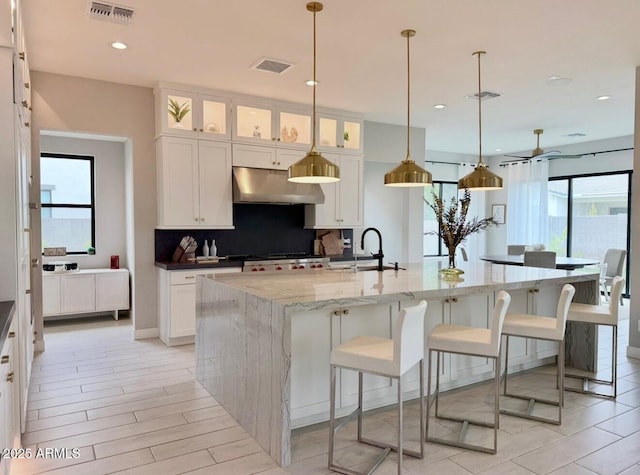 kitchen featuring visible vents, white cabinetry, and under cabinet range hood