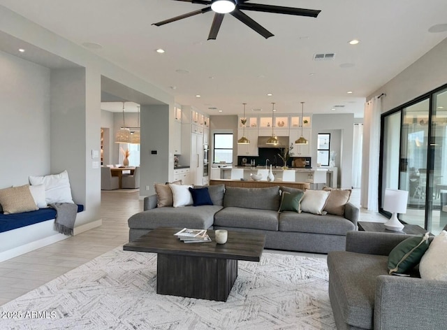 living room with ceiling fan, recessed lighting, baseboards, light wood-type flooring, and visible vents