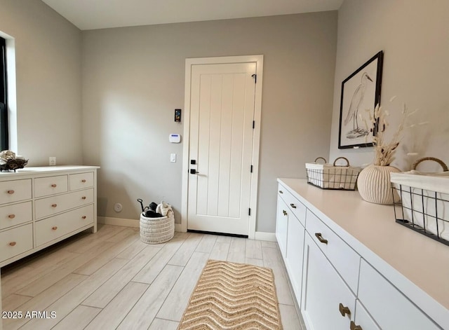 interior space featuring baseboards and light wood finished floors