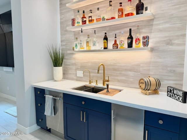 bar featuring stainless steel dishwasher, indoor wet bar, baseboards, tasteful backsplash, and a sink