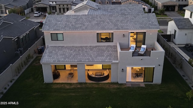 back of house featuring a lawn, a fenced backyard, stucco siding, and a residential view