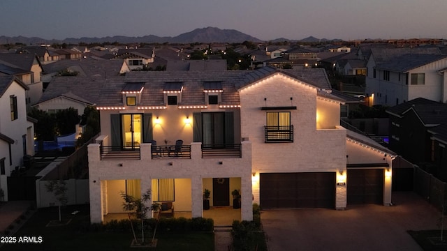 view of front of home featuring an attached garage, fence, a residential view, and a balcony