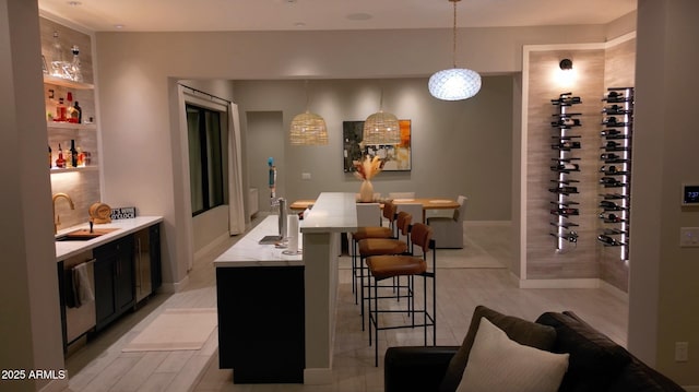 bar with a sink, wet bar, baseboards, stainless steel dishwasher, and pendant lighting